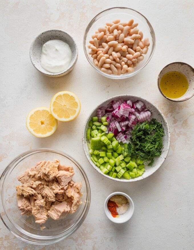Prep bowls full of tuna, white beans, lemon, celery, red onion, dill, and more ingredients for tuna salad.