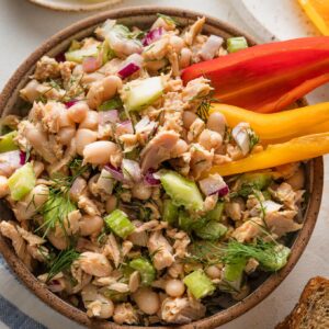 Bowl full of lemon dill tuna salad with two crisp bell pepper boats stuck in for snacking.