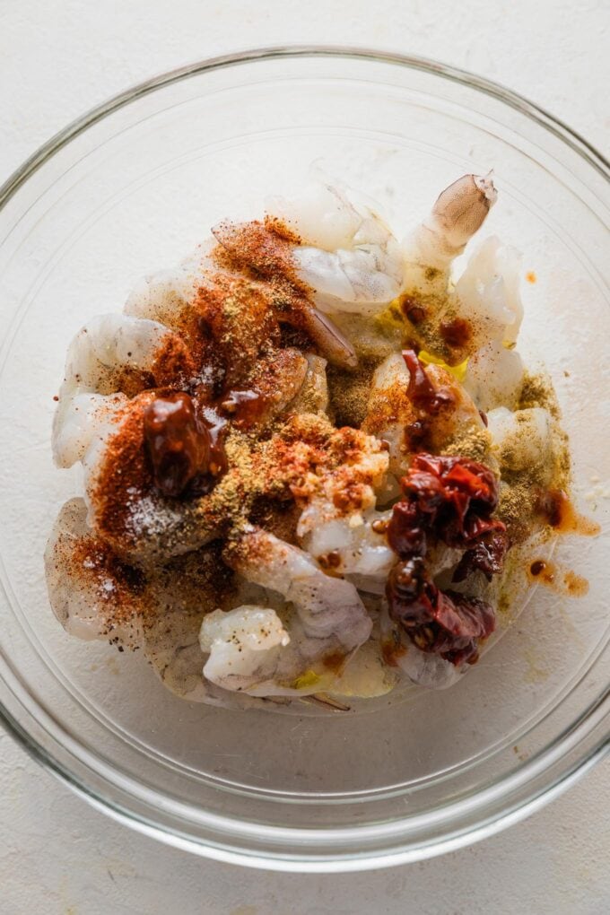 Raw shrimp in a bowl topped with Tex-Mex style seasonings.