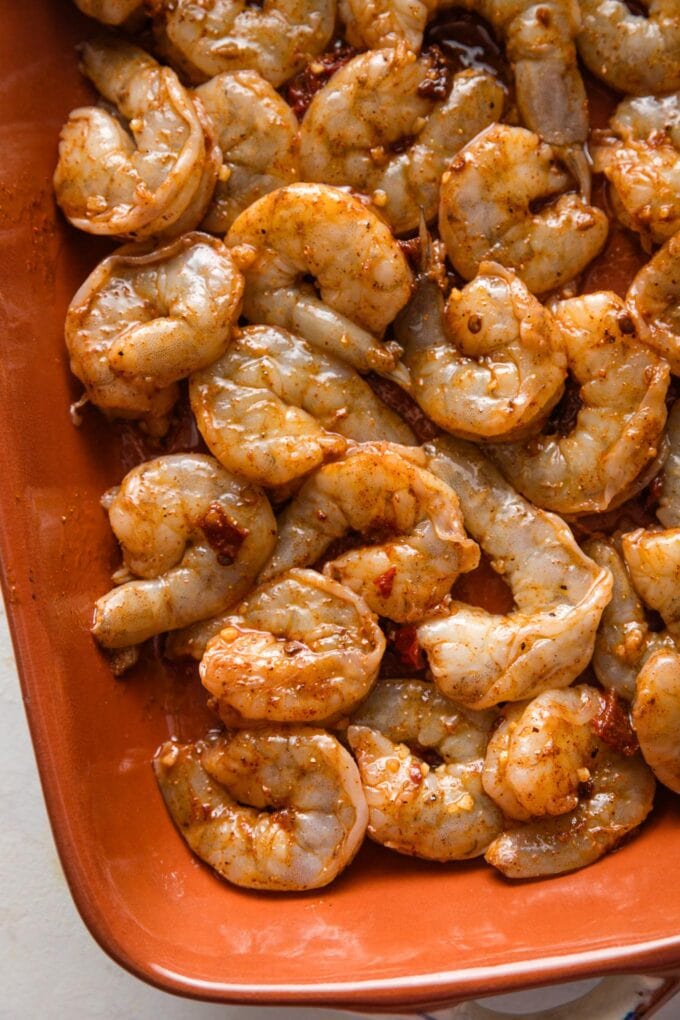Seasoned raw shrimp in a baking pan.