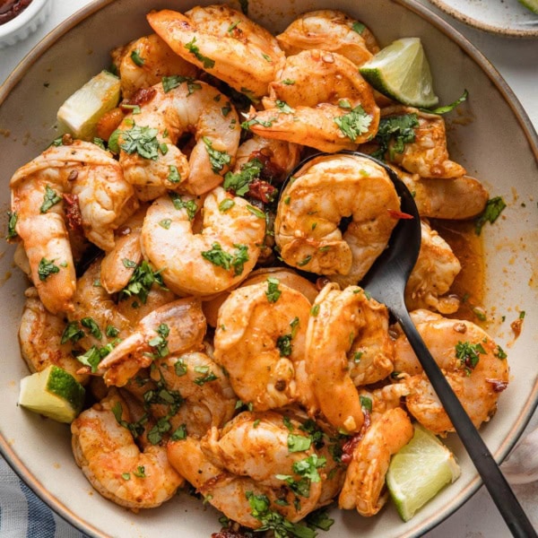 Bowl full of oven-baked chipotle shrimp with fresh cilantro scattered on top.