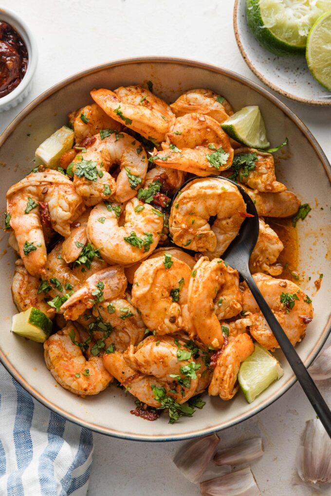Bowl full of oven-baked chipotle shrimp with fresh cilantro scattered on top.