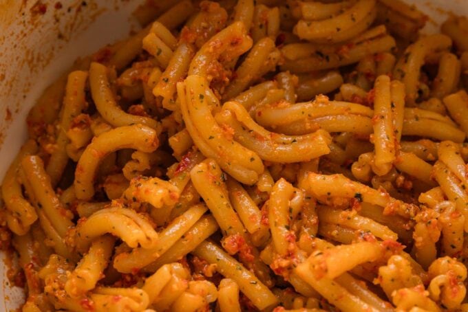 Cavatelli coated in a light red pesto sauce.