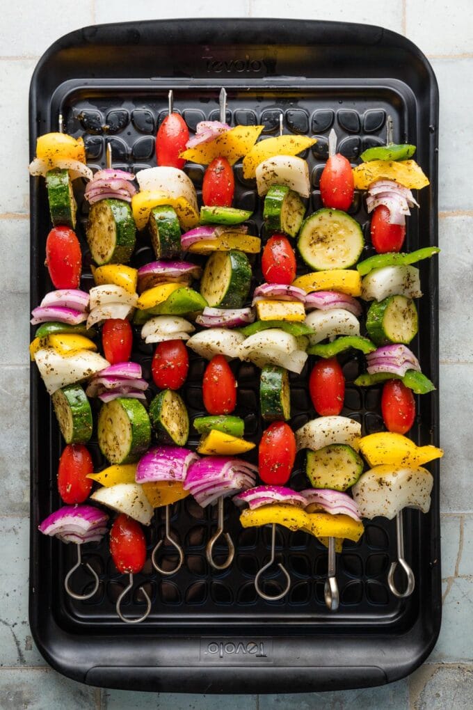 Grilling tray arranged with veggie kabobs, ready to cook.