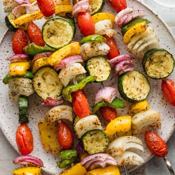 Veggie skewers grilled and resting on a plate.