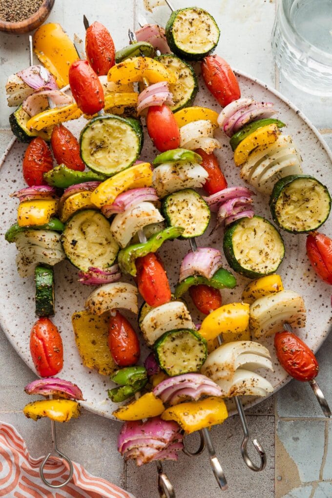 Veggie skewers grilled and resting on a plate.