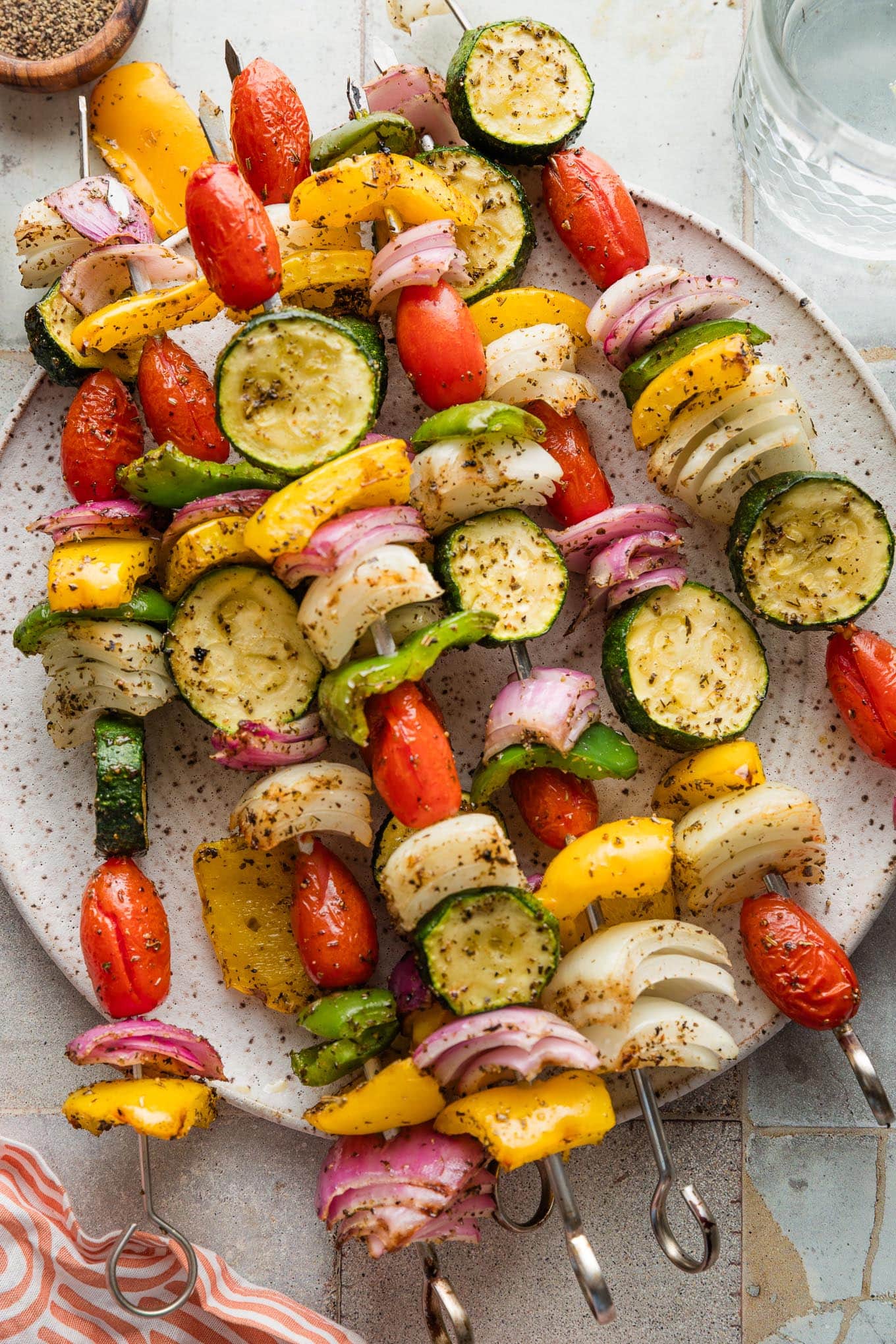 Veggie skewers grilled and resting on a plate.