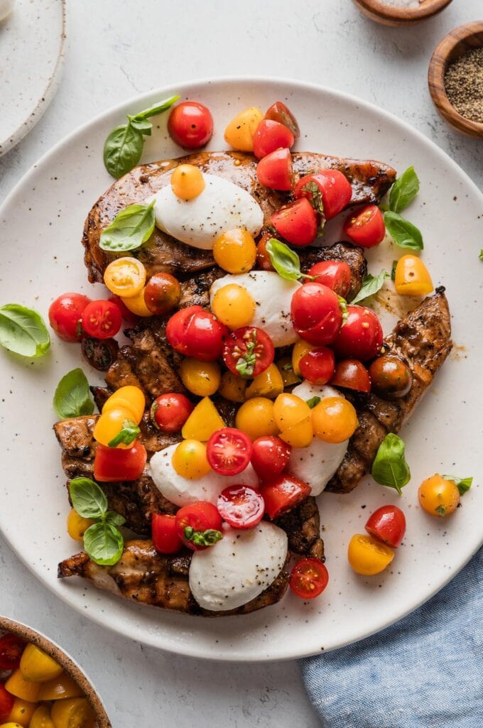 Platter filled with grilled balsamic chicken topped with mozzarella medallions, quick-marinated tomatoes, and fresh basil leaves.