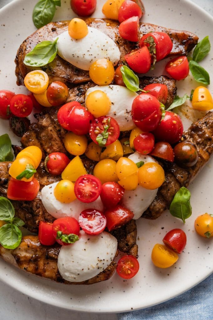 Platter filled with balsamic Caprese chicken topped with fresh basil and extra olive oil and pepper.