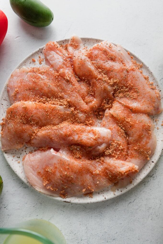 Plate of seasoned chicken cutlets, ready to cook.