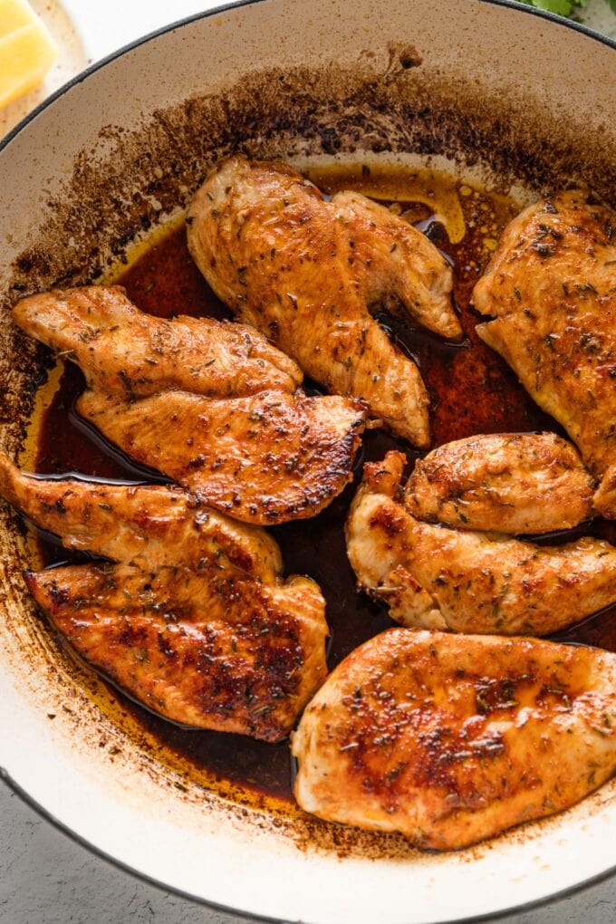 Seared chicken cutlets in a pan.