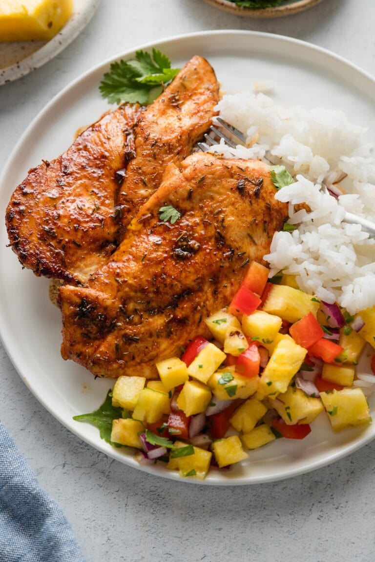 Plate of chicken cutlets pan-seared with a brown sugar spice rub, pineapple salsa, and rice.