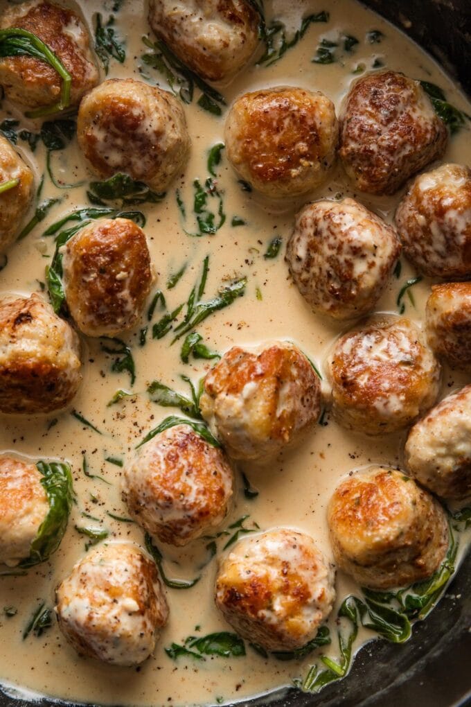 Close up of chicken Florentine meatballs in cream sauce in a pan.