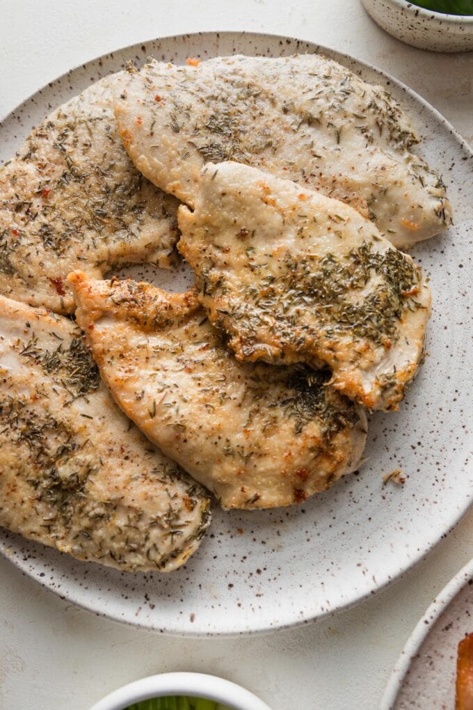 Pan-seared chicken breasts resting on a plate.
