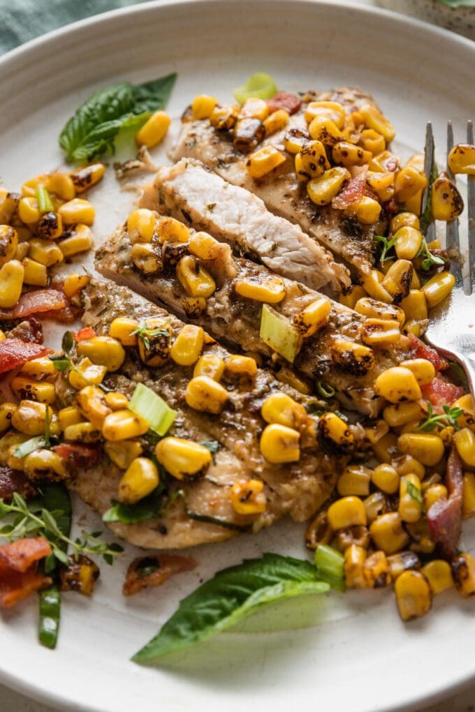 Close up of brown butter chicken and corn on a plate.
