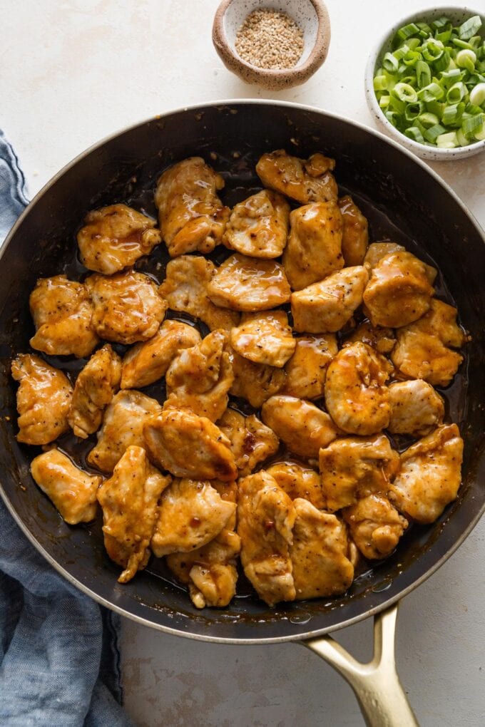 Chicken pieces coated and tossed in a homemade orange sauce in a large skillet.
