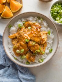 Countertop set with a dish of Asian-inspired orange chicken served over rice.