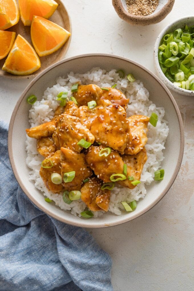 Countertop set with a dish of Asian-inspired orange chicken served over rice.