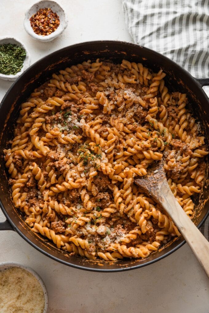 Easy rotini pasta recipe with homemade tomato meat sauce ready to serve from a large, deep cast iron skillet.