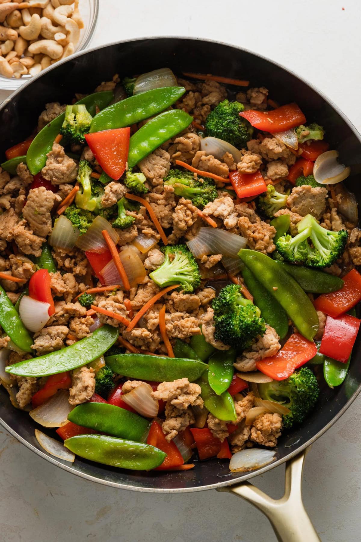 Large skillet full of a kid-friendly, mild ground chicken stir fry, with a sauce of soy sauce and honey plus a rainbow of veggies to choose from.