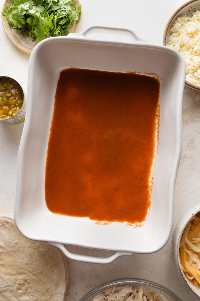 A small amount of enchilada sauce spooned into the bottom of a baking dish.
