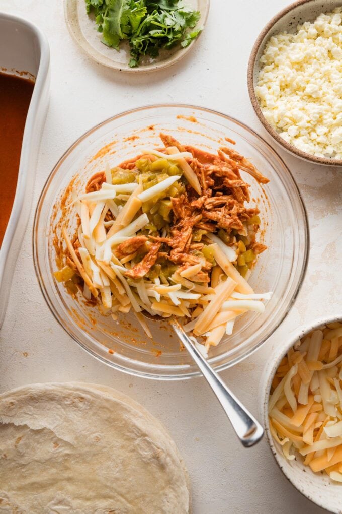 Enchilada mixture coming together in a small clear glass prep bowl.