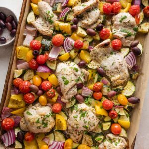 Sheet pan full of Greek chicken and veggies.