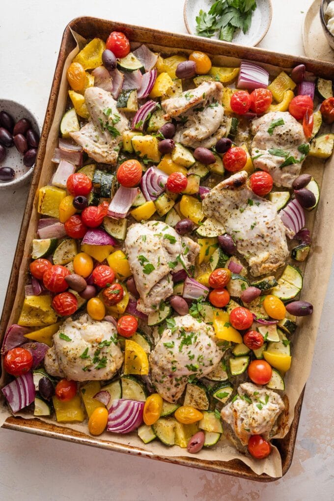Sheet pan full of Greek chicken and veggies.