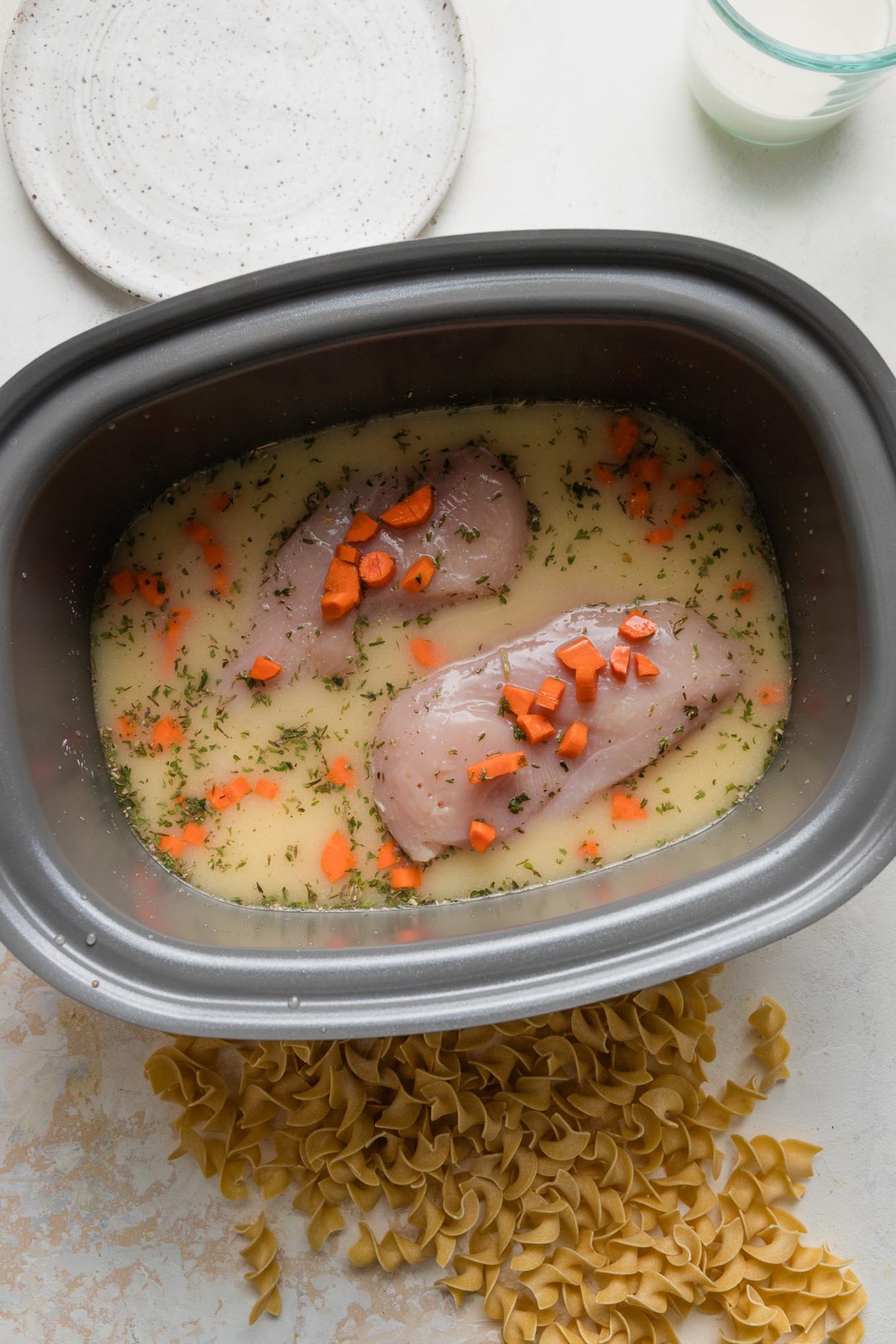 Chicken breasts added to slow cooker but not yet cooked.