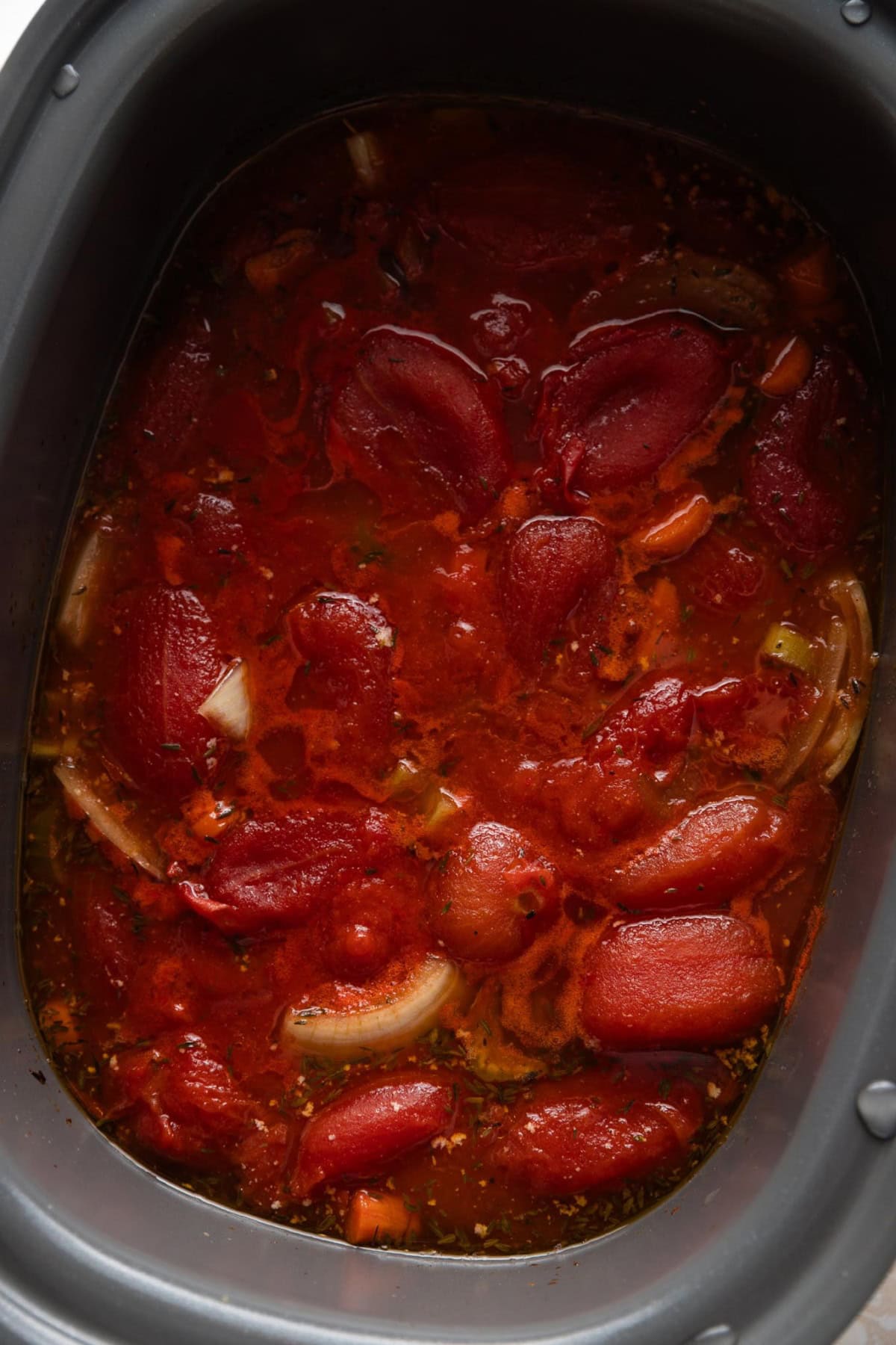 Tomato soup ingredients simmered all day in a slow cooker bowl.