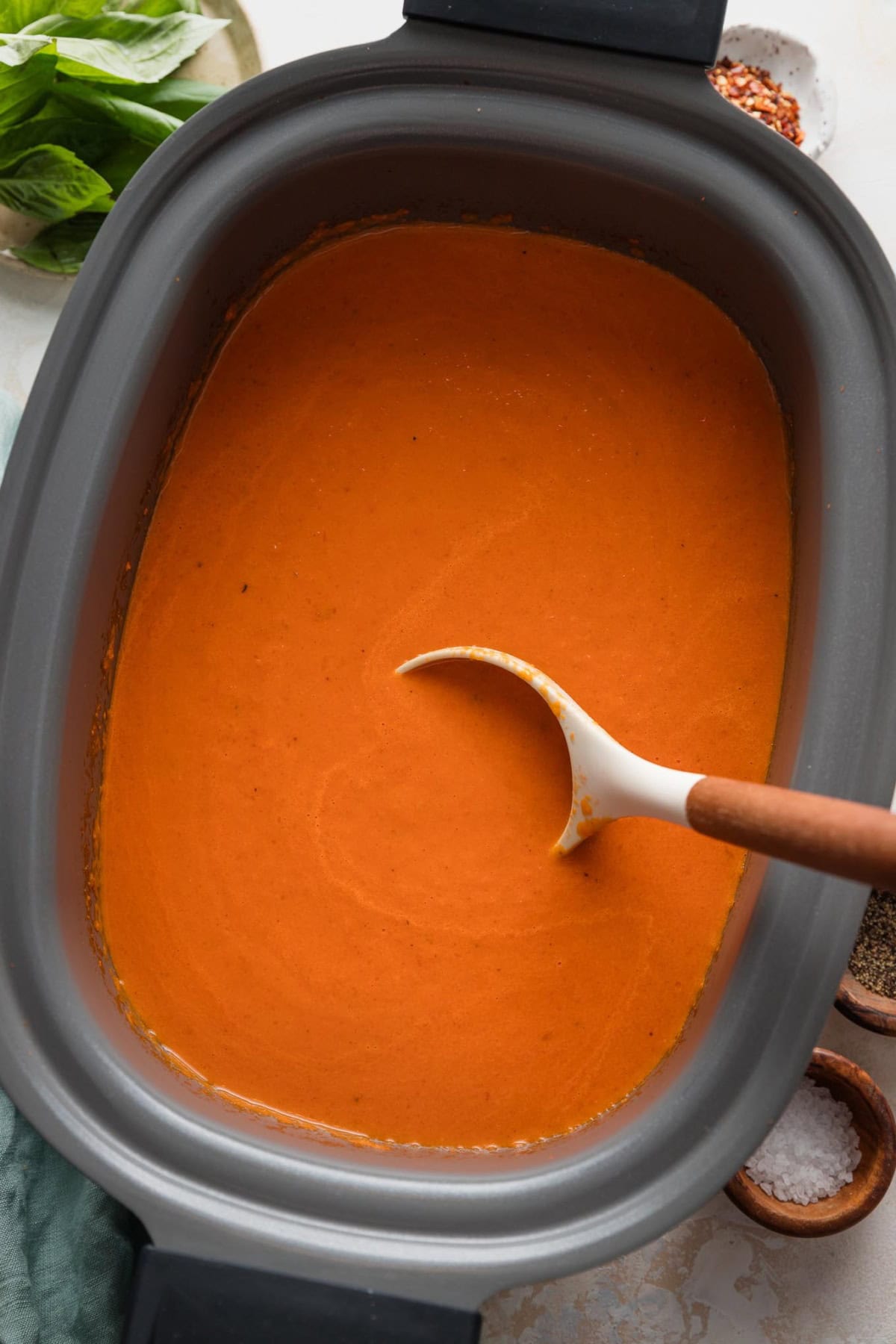 Ladle stirring a batch of slow cooker tomato soup.