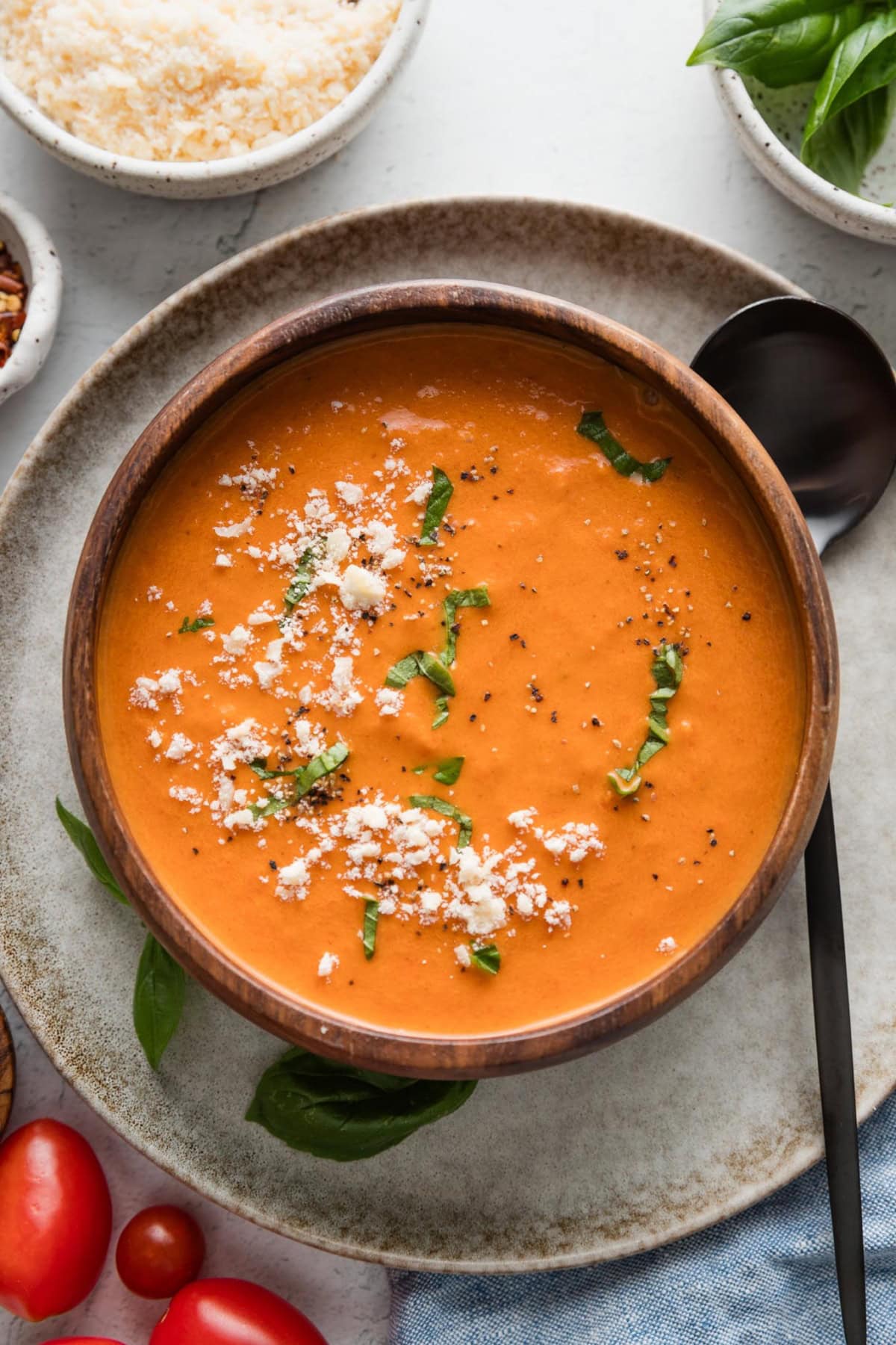 Bowl of tomato soup made in the Crockpot served with fresh basil and Parmesan.