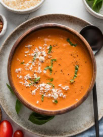 Bowl of tomato soup made in the Crockpot served with fresh basil and Parmesan.