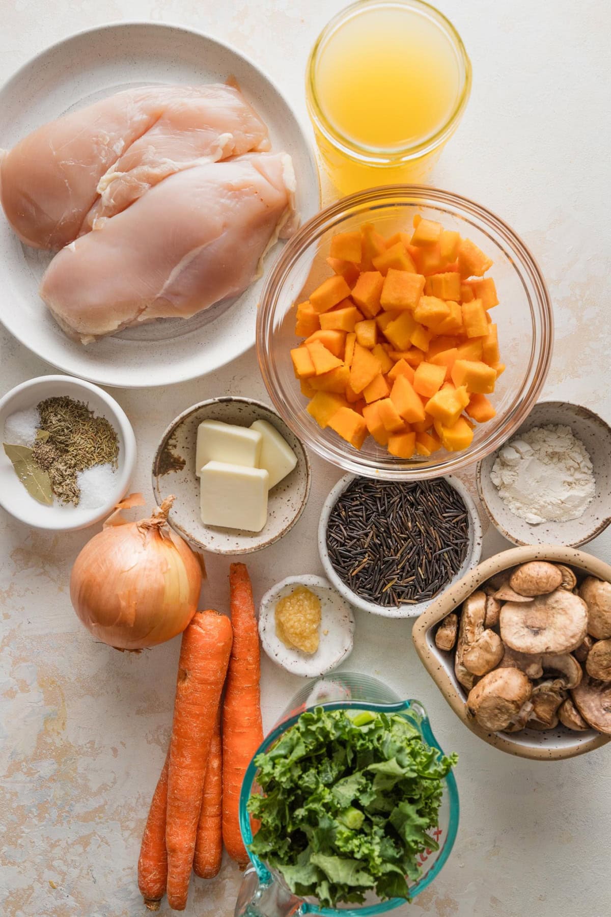 Overhead view of prep bowls with chicken breasts, wild rice, and lots of veggies for making into a hearty fall soup.