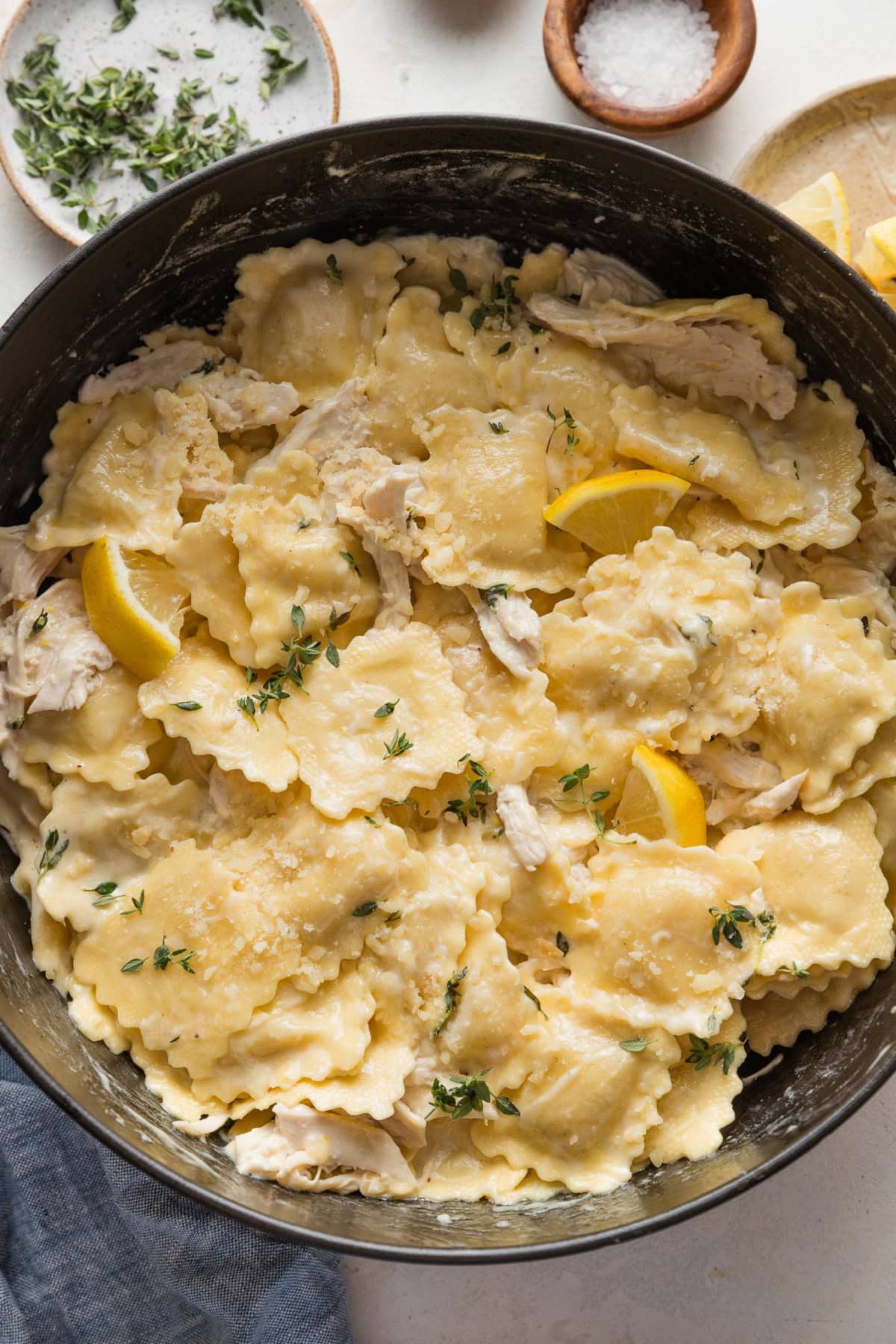 Dark cast iron skillet filled with a one pot dish of creamy lemon ravioli with chicken.