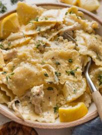 Close up of a fork picking up a bite of creamy lemon chicken ravioli.
