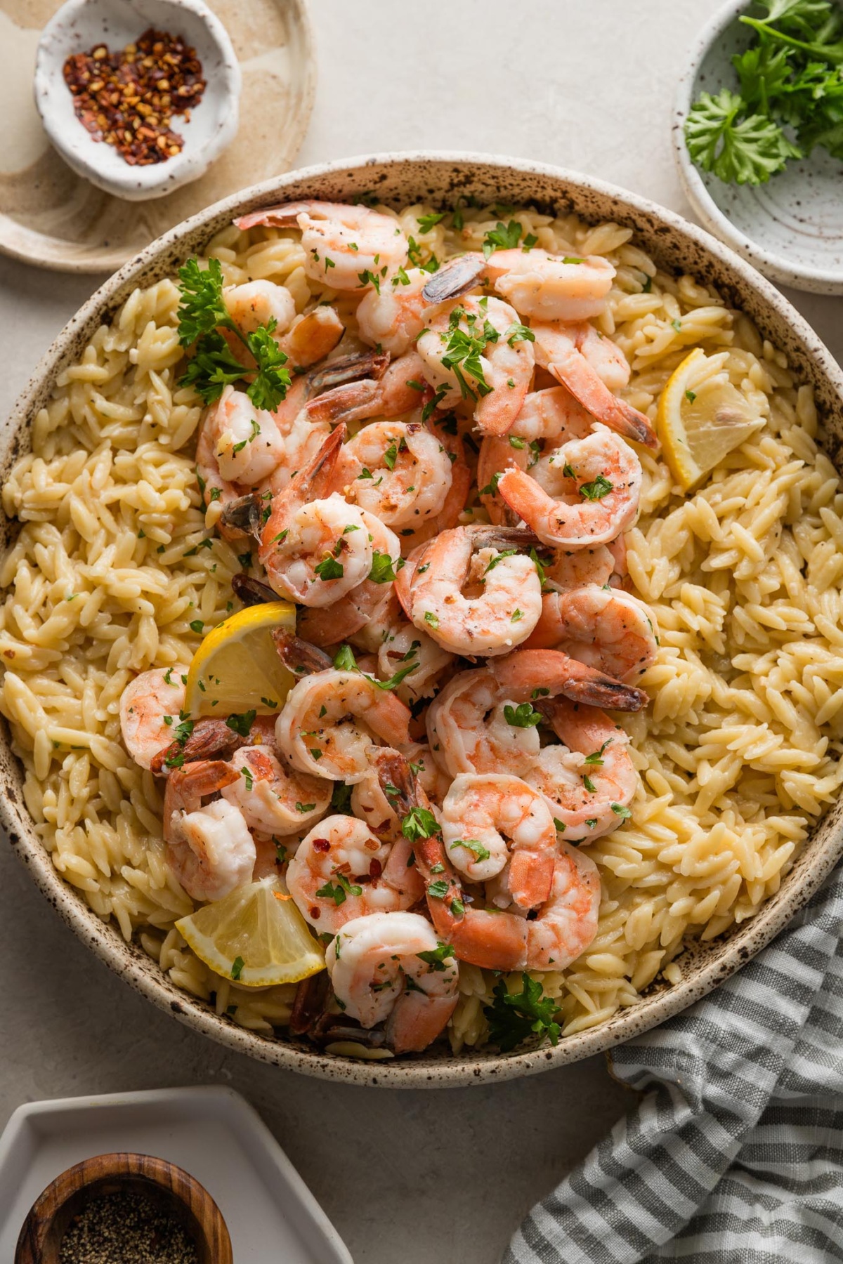 Speckled ceramic bowl filled with shrimp scampi topped with fresh parsley.