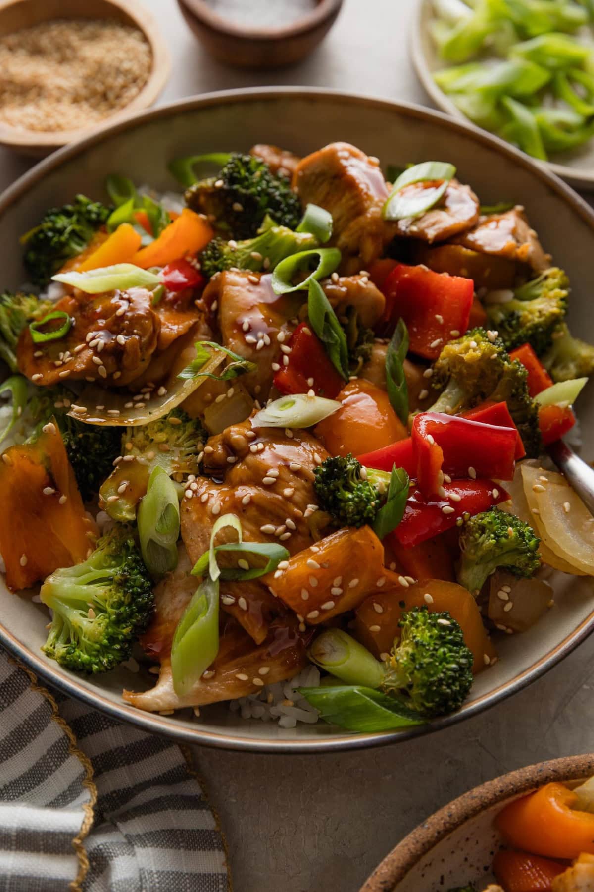 Close up of teriyaki chicken and veggies prepared on a sheet pan and served in a bowl with rice.