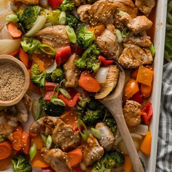 Large enameled sheet pan filled with a one pan baked teriyaki chicken and veggies.