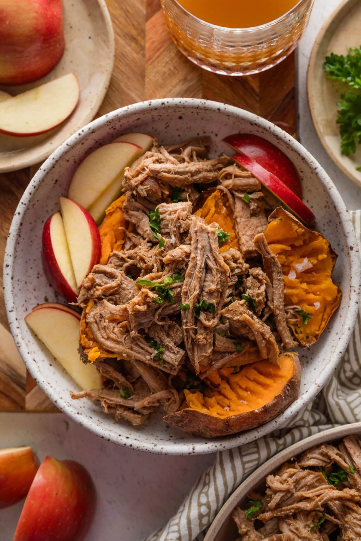 Bowl of pulled pork, apple slices, and baked sweet potato.